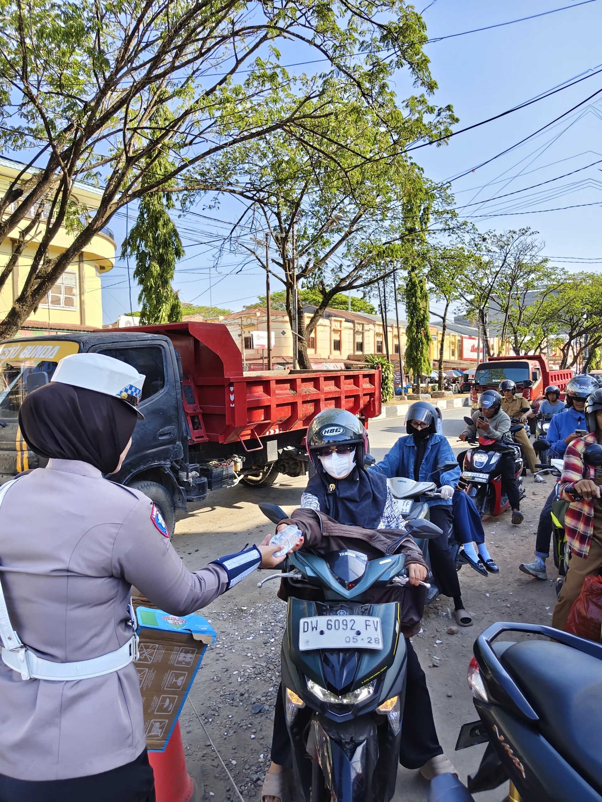 Wujud Polri Humanis, Polwan Satlantas Polres Bone Bagikan Air Mineral ke Pengendara yang Antre BBM